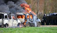 French gendarmes' stand next to gendarmes' cars burning on the sideline of a demonstration called by the collective 