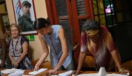 Electoral officials check the voters roll at a polling station in Havana, on March 26, 2023, during the country's legislative election.  (Photo by ADALBERTO ROQUE / AFP)
