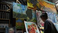 This picture taken on February 19, 2023 shows artist Deng Fei painting a replica of Vincent van Gogh's Sunflowers in an alley at Dafen village, in Shenzhen, in China southern Guangdong province. Photo by GREG BAKER / AFP