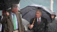 Britain's King Charles III (right) uses an umbrella to protect against the pouring rain as he walks with manager of the Oekodorf Brodowin eco-village Ludolf von Maltzan after visiting the village including an organic farm with milking parlour and cow shed, in Brodowin, eastern Germany, on March 30, 2023.  (Photo by Matthias Schrader / POOL / AFP)
