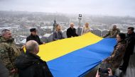 People hold a Ukrainian flag atop Lviv City Hall tower during an event to celebrate 33rd anniversary of raising the national flag in 1990, in Lviv, on April 3, 2023. (Photo by YURIY DYACHYSHYN / AFP)