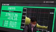 A man walks past an electronic quotation board displaying the closing numbers of share prices of the Tokyo Stock Exchange in Tokyo on April 5, 2023. (Photo by Kazuhiro Nogi / AFP)