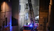 A firetruck extends a ladder at the scene of a collapsed building on 'rue Tivoli', in Marseille, southern France, on April 10, 2023. (Photo by Nicolas Tucat / AFP)