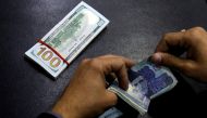 File Photo: A currency trader counts Pakistani Rupee notes as he prepares an exchange of US dollars in Islamabad, Pakistan, December 11, 2017. (REUTERS/Caren Firouz)