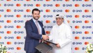QNB and Mastercard officials exchange the agreement.