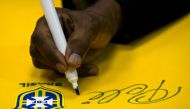 Brazilian football legend Edson Arantes do Nascimento, known as Pele, signs a Brazilian national team shirt during a press conference at Volkswagen plant in Sao Bernardo do Campo, in the metropolitan area of Sao Paulo, Brazil. Photo by Nelson ALMEIDA / AFP
