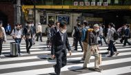 People cross a street in Yurakucho district of Tokyo on April 28, 2023. (Photo by Yuichi Yamazaki / AFP)