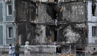 People pay their respects in front of a damaged multistory residential building, where a Russian strike killed 23 people, in Uman, Cherkasy region, on April 30, 2023. (Photo by Genya Savilov / AFP)
