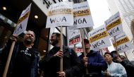 Demonstrators carry signs during a screenwriter's strike in New York City on May 2, 2023. (Photo by Leonardo Munoz / AFP)
