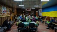 Local residents sit in a volunteer-run shelter, providing access to laundry and bathroom facilities where they can warm up, charge their phones, drink hot tea and receive humanitarian aid in the town of Orikhiv, in the Zaporizhzhia region, on May 7, 2023, amid the Russian invasion of Ukraine. (Photo by Dimitar Dilkoff / AFP)