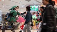 This photo taken on May 8, 2023 shows people walking past an illustration (L) for Japanese gaming giant Nintendo's long-running 