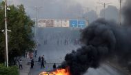 A car is seen burning along a road as Pakistan Tehreek-e-Insaf (PTI) party activists and supporters of former Pakistan's Prime Minister Imran block a road during a protest against the arrest of their leader in Karachi on May 9, 2023. (Photo by Asif Hassan / AFP)