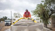 A man sits on top of a municipal tank truck while filling it with water in Hammanskraal on May 23, 2023. (Photo by Michele Spatari / AFP)