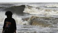 A man walks away from the seafront as high tidal waves hit the coast in Mumbai on June 13, 2023, as cyclone Biparjoy makes its way across the Arabian Sea towards the coastlines of India and Pakistan. (Photo by Punit Paranjpe / AFP)
