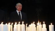 Russia's President Vladimir Putin stands in front of candles at the memorial 