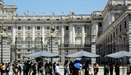 Tourists protect themselves of the sun while they visit the Royal Palace in Madrid city centre under very high temperatures, on June 26, 2023 as Spain is facing its first heatwave of the summer, with temperatures expected to exceed 44 degrees locally in the south of the country. (Photo by Thomas Coex / AFP)