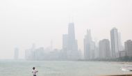 A jogger runs along the shoreline of Lake Michigan with heavy smoke from the Canadian wildfires in the background, on June 27, 2023, in Chicago, Illinois. (Photo by KAMIL KRZACZYNSKI / AFP)
