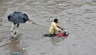 A motorcyclist pushes his bike through a flooded street after heavy rainfall in Lahore on July 5, 2023. (Photo by Arif Ali / AFP)
