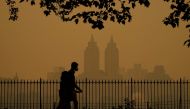 People walk in Central Park as smoke from wildfires in Canada cause hazy conditions in New York City on June 7, 2023. (Photo by Timothy A Clary / AFP)