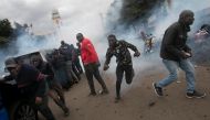 Protestors retreat from a cloud of teargas after police fired canisters at the convoy of opposition leaders led by Raila Odinga during demonstrations against the high cost of living in Nairobi on July 7, 2023. (Photo by Tony Karumba / AFP)