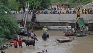 People move their belongings to safety at a bridge over the flooded Yamuna River after heavy monsoon rains in New Delhi on July 12, 2023. Photo by Arun SANKAR / AFP