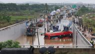 South Korean rescue workers search for missing persons near a bus along a deluged road leading to an underground tunnel where some 15 cars were trapped in flood waters after heavy rains in Cheongju on July 16, 2023. Photo by YONHAP / AFP)