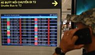 A man uses his mobile phone as a flight information board displays flights cancelled due to typhoon Talim at Noi Bai international airport in Hanoi on July 18, 2023. Photo by Nhac NGUYEN / AFP