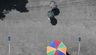 People shelter from the sun with umbrellas as they walk past a vendor in Manila on August 10, 2023. Photo by Ted ALJIBE / AFP