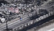 An aerial image taken on August 10, 2023 shows a person walking down Front Street past destroyed buildings burned to the ground in Lahaina in the aftermath of wildfires in western Maui, Hawaii. Photos by Patrick T. Fallon / AFP