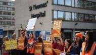 People hold British Medical Association (BMA) branded placards calling for better pay, as they stand on a picket line outside St Thomas' Hospital in central London on August 11, 2023. (Photo by Henry Nicholls / AFP)