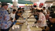 Volunteers prepare free meals to donate to West Maui families affected by wildfires, at the University of Hawaii Maui College in Kahului, central Maui, Hawaii on August 13, 2023. (Photo by Yuki Iwamura / AFP)