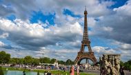 Members of the public take photographs in front of the Eiffel Tower in Paris on August 16, 2023. (Photo by MIGUEL MEDINA / AFP)