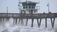 People stand on a pier over the Pacific Ocean with Tropical Storm Hilary approaching in San Diego County on August 20, 2023 in Imperial Beach, California. (Photo by Mario Tama/ AFP)