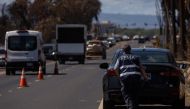 A Federal Emergency Management Agency (FEMA) agent is seen as search and recovery team members check charred buildings and cars in the aftermath of the Maui wildfires in Lahaina, Hawaii, on August 18, 2023. (Photo by Yuki IWAMURA / AFP)
