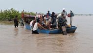 People with their belongings wade through the flood affected area of Chanda Singh Wala village in Kasur district on August 22, 2023. (Photo by Arif ALI / AFP)