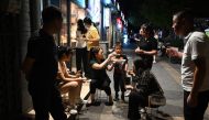A family eats snacks outside a restaurant in Beijing on August 26, 2023. (Photo by GREG BAKER / AFP)
