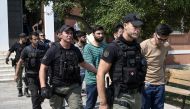 The group of 13 Pakistani and Syrian men charged with illegal entry and attempted arson are escorted at the court house ahead of their hearing in Alexandroupoli on August 25, 2023. (Photo by Sakis MITROLIDIS / AFP)
