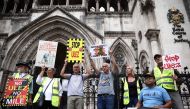 Demonstrators hold placards as they protest against the expansion of the Ultra Low Emission Zone (ULEZ) in London, outside the Royal Courts of Justice, Britain's High Court, in central London on July 28, 2023. Photo by Henry Nicholls / AFP
