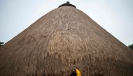 A traditional guard stands in front of one of the buildings belonging to the Kasubi Royal Tombs in Kampala, Uganda on June 13, 2023. (Photo by Stuart Tibaweswa / AFP)