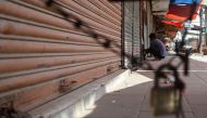 A shopkeeper locks a shop along a roadside in Karachi on September 2, 2023 (Photo by Rizwan Tabassum / AFP)