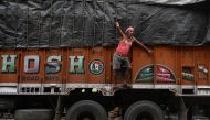 A worker ties rope around a loaded truck transporting food grains and other products to retail outlets across the city, at a wholesale market in Kolkata on August 31, 2023. Photo by DIBYANGSHU SARKAR / AFP