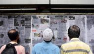 In this photograph taken on September 1, 2023, pedestrians read Bangladesh's local newspapers displayed along a street in Dhaka. (Photo by Munir Uz Zaman / AFP) /