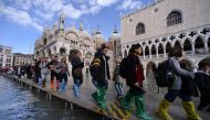 People walk on a footbridge across the flooded St. Mark's Square by St. Mark's Basilica (rear) and the Doge's palace (right) on November 14, 2019 in Venice. (Photo by Filippo Monteforte / AFP)