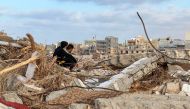 People sit among the rubble in Libya's eastern city of Derna on September 20, 2023, following a deadly flash flood. (Photo by Abu Bakr AL-SOUSSI / AFP)