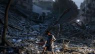 A man walks atop the rubble of a tower destroyed in an Israeli air stike in Gaza City on October 7, 2023. (Photo by MOHAMMED ABED / AFP)
