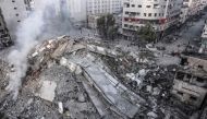People walk around the ruins of a building destroyed in Israeli airstrikes in Gaza City on October 8, 2023. (Photo by Mohammed Abed / AFP)