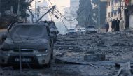 People walk past ruins on a street impacted by Israeli airstrikes in Gaza City on October 8, 2023. Photo by MAHMUD HAMS / AFP