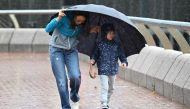 A woman and a child struggle with strong winds as Hong Kong hoisted typhoon signal no 8 around noon on October 8, 2023 as typhoon Koinu skirted by after the financial hub was affected again by a super typhoon and historic rainstorm last month. Photo by Peter PARKS / AFP
