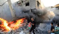 A Palestinian man uses a fire extinguisher to douse a fire following an Israeli strike, in Khan Yunis in the southern Gaza Strip on October 14, 2023. (Photo by Yasser Qudih / AFP)