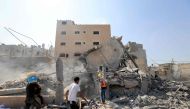 Palestinians survey the rubble of a collapsed building following an Israeli strike, in Khan Yunis in the southern Gaza Strip on October 14, 2023, amid the ongoing battles between Israel and the Palestinian Islamist group Hamas. Photo by Mahmud Hams/ AFP